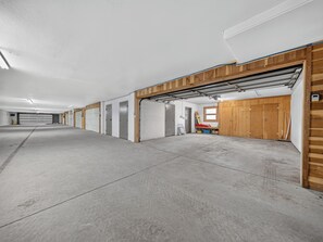 Een ruime overdekte parkeergarage met betonnen vloeren en houten wanden.
