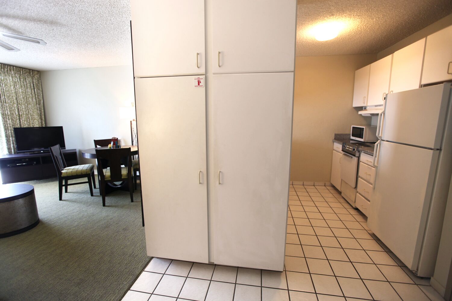 Cocina compacta con refrigerador, microondas y estufa. Cuenta con un comedor con mesa y sillas.