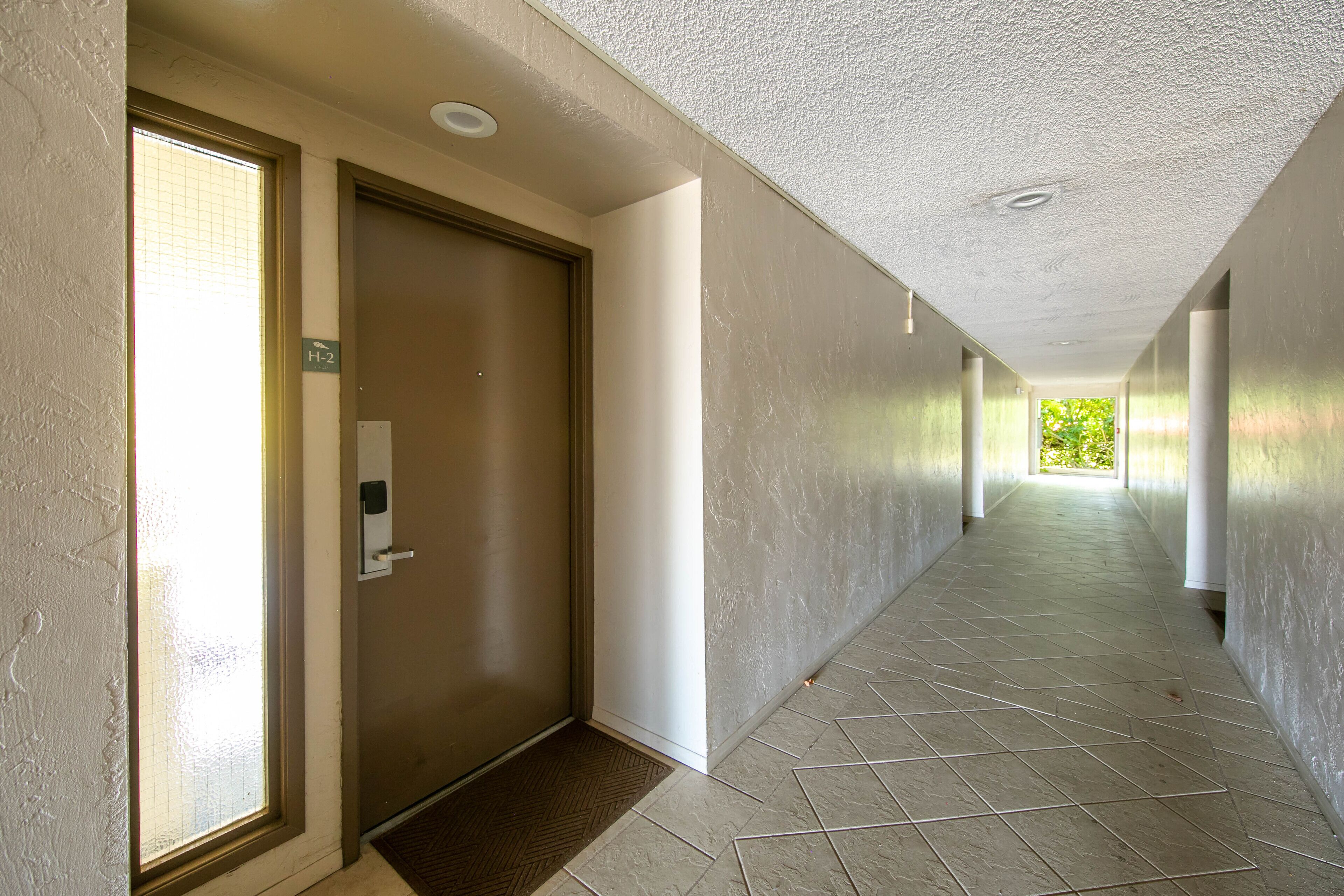 A hallway with a door marked "H-2," a handrail, and a tiled floor.