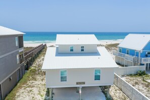 A beachfront property with a two-story house, a wooden deck, and a clear view of the ocean. - 4BR Beachfront Getaway, Beat the Crowds! (Gulf Shores)