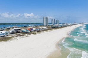 Un hôtel situé sur la côte, avec des chambres donnant sur la plage, une jetée et, en arrière-plan, des immeubles de grande hauteur.