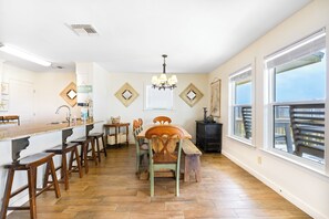 A kitchen with a wooden bar, stools, a dining table, and chairs.