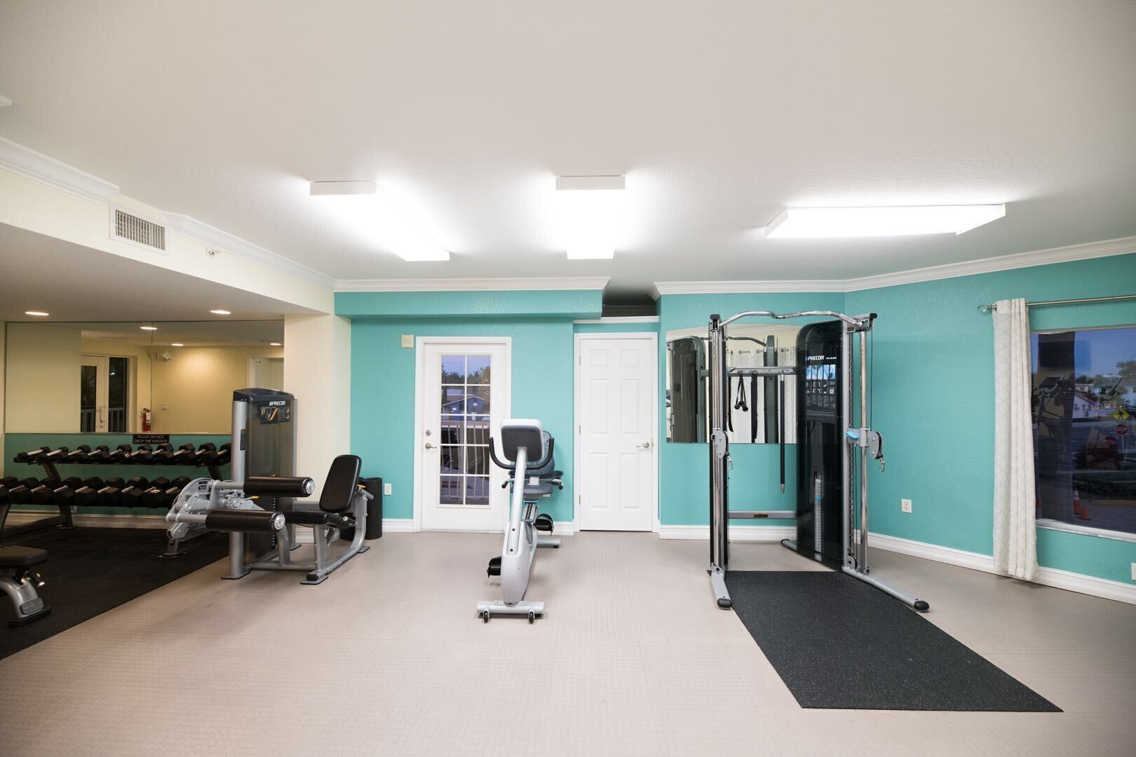A gym with dumbbells, exercise machines, and a door.