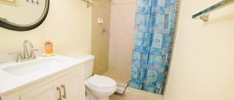 Un baño con inodoro, lavabo y cortina de ducha.