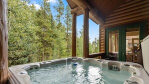 Un jacuzzi en una terraza de madera con vista a un bosque.