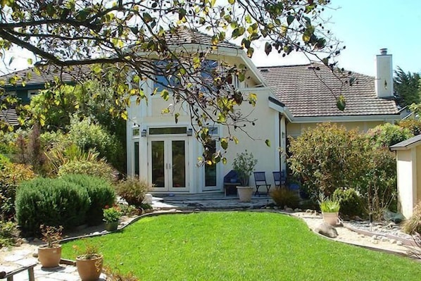 A house with a well-maintained lawn, a patio area, and a variety of plants and shrubs.