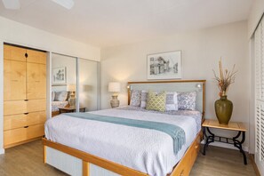 A neatly arranged bedroom with a bed, bedside tables, a mirror, and a framed picture on the wall.