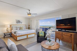 A bedroom with a bed, a TV, a balcony with a view, and a dining area.