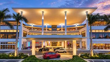 A modern hotel with a multi-level structure, a covered entrance, and a parking area with cars.