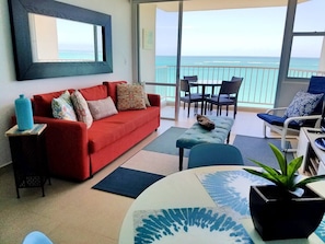 Relax in this stylish living room with a sofa, coffee table, and sliding glass door leading to a balcony with ocean views.