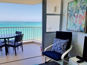 Enjoy ocean views from this room's balcony, featuring a dining table, sofa, and TV.
