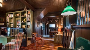 A cozy room with wooden floors, a fireplace, a bookshelf, and a dining area.