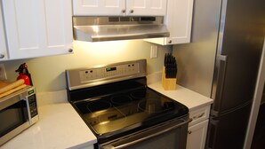 A kitchen with a stainless steel stove, microwave, and refrigerator.
