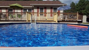 A swimming pool with a wooden deck and a house in the background. - GORGEOUS AND MODERN describes this 6 bedroom home . (Warrensburg)