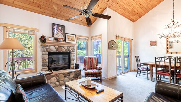 A spacious living room with a stone fireplace, leather furniture, and a ceiling fan. - Spacious 4BR Townhome | 2 Living Rooms and Walk to Ski Area! (Steamboat Springs)