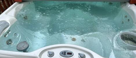Un jacuzzi con panel de control, asiento integrado y cubierta.