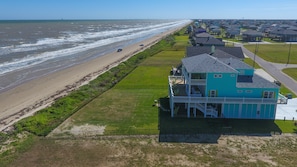 A coastal house with a balcony overlooking the beach.