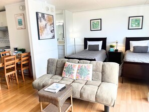 A cozy room with a sofa, a small table, a bed with a headboard, and a nightstand. - Ocean/Waikiki Views-Spacious Modern unit+parking "in the heart of Waikiki" (Honolulu)