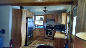 Una cocina con armarios de madera, un refrigerador de acero inoxidable, una estufa y un microondas.