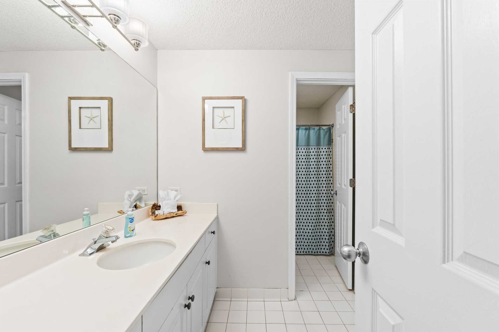 Un baño con un lavabo blanco, un espejo y cuadros en la pared.