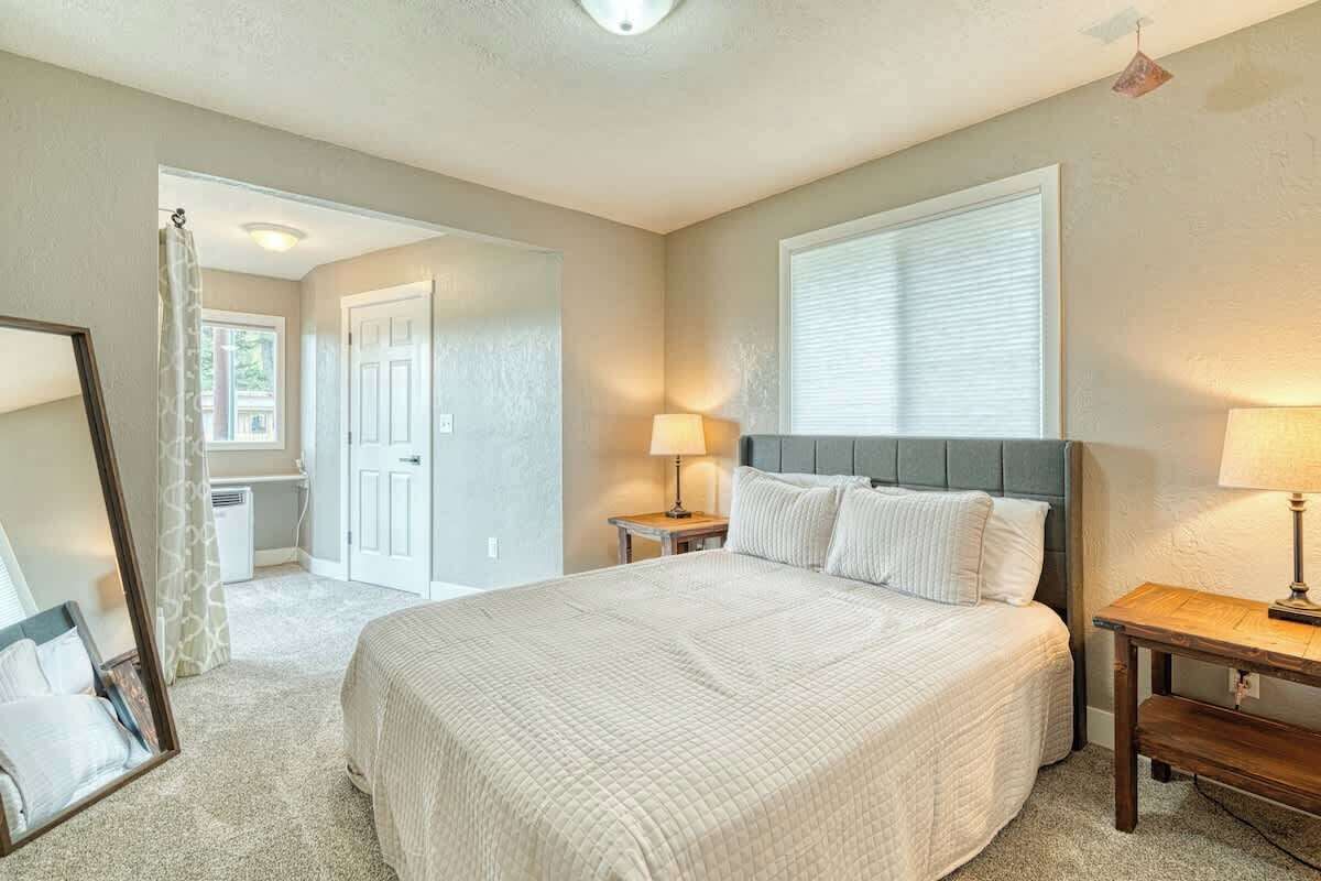 A bedroom with a large bed, bedside tables, a mirror, and a window.