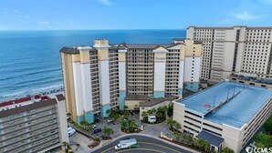 Un grand hôtel à plusieurs étages, doté d’un parking et offrant une vue sur l’océan.