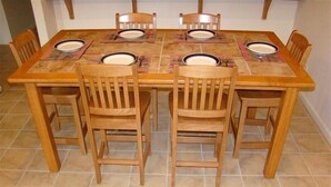 Une table à manger entourée de six chaises en bois, chacune étant agrémentée d’un set de table et d’une assiette.