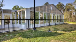 Una estructura moderna de invernadero con paneles de vidrio amplios y una cerca de metal.