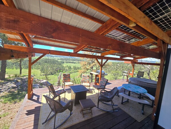 A covered outdoor patio with wooden furniture, a grill, and a scenic view of a forested valley. - Reflection 37ft RV @EvansCliff w/Hot Tub on Deck, Beautiful Canyon Overlook! (Hot Springs)