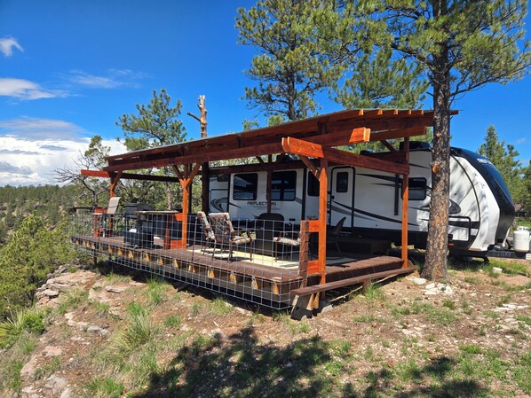 Un véhicule récréatif doté d’un patio couvert, d’un barbecue et offrant une vue panoramique sur les montagnes.