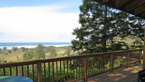 A wooden deck with a view of the ocean and trees. - Ocean View Oasis Retreat. Comfort, plus great views! Sleeps 4. (Neskowin)