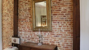 A room with a brick wall, a wooden bench, a mirror, and a decorative glass object. - Vintage Townhome / Heart of Fells Point (Baltimore)