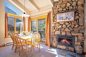 Un comedor con chimenea de piedra, sillas de madera y una mesa dispuesta para cuatro.
