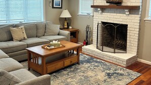 A living room with a fireplace, a sofa, a coffee table, and a rug. - Beachside Location at Lecount Hollow With A/C (Wellfleet)
