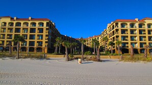 Ett hotell vid stranden med flera balkonger och palmer.