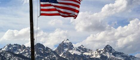 An American flag on a flagpole with a mountain range in the background.