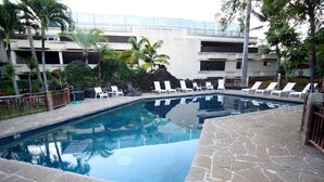 A swimming pool with lounge chairs, surrounded by stone tiles and palm trees. - Remodeled Condo 300 Ft From The Ocean!!!  (Koloa)