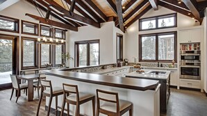 A spacious kitchen with a large island, wooden beams, and large windows.