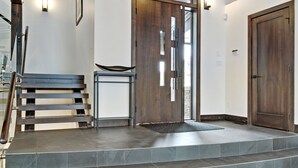 A staircase leading to a wooden door with a glass panel, a bench, and a small table with a rug.