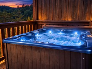 Ein Whirlpool auf einer Holzterrasse mit Blick auf Bäume und einen Sonnenuntergang.