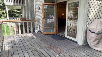 A wooden deck with a glass door leading to a room.