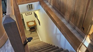 Ein Holzinnenraum mit einer eingebauten Badewanne, einer mit Teppich ausgelegten Treppe und einer kleinen Sitzecke mit Tisch und Stühlen.