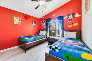Quarto com duas camas, paredes vermelhas e decoração temática da Disney.