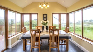 Comedor con una mesa preparada para cuatro personas, rodeado de amplios ventanales con vistas al exterior.