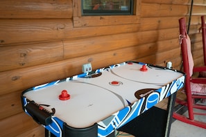 A table hockey game in a wooden cabin with a window above it.