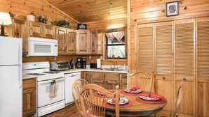 A kitchen with wooden cabinets, a microwave, stove, and a dining table set with plates and chairs.
