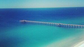 A long pier extending into a calm sea with a clear sky.