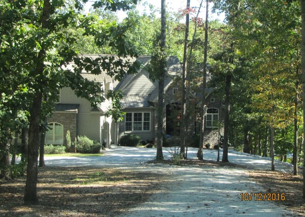 A large, two-story house with a stone facade and multiple windows, surrounded by trees and a snow-covered driveway. - Lake Front, Quiet, Private cove on 4.75 acres, Canoe, 2 Kayak, 2 boat docks (Seneca)