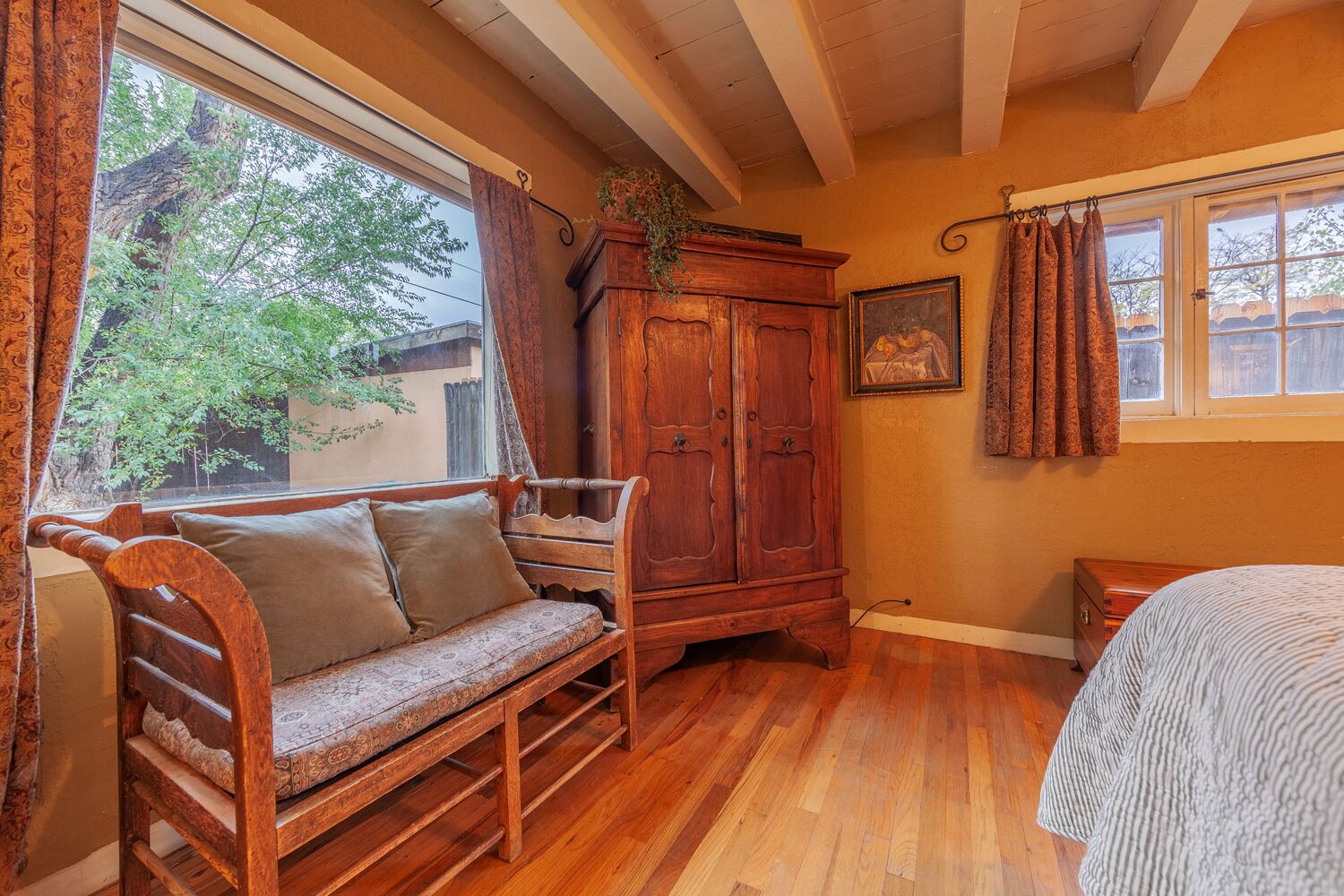 A cozy room with a wooden bench, a cabinet, and a bed.