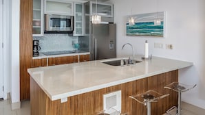 Una cucina moderna con isola centrale, elettrodomestici in acciaio inossidabile e un quadro raffigurante l'oceano.